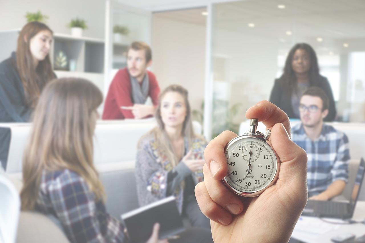Team brainstorming session in an office with a stopwatch in focus, highlighting workplace productivity and time pressure.